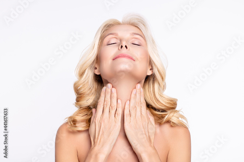 Fotografie Portrait of attractive dreamy woman touching neck applying cream moisturizing we