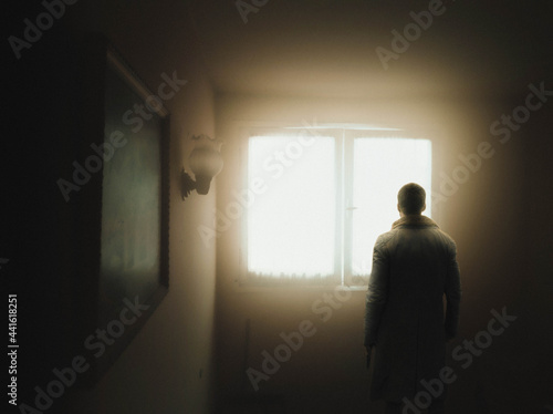 man standing in front of window with warm light