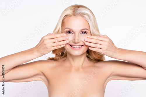 Portrait of attractive cheerful woman with touching clean clear skin applying facial serum isolated over white color background