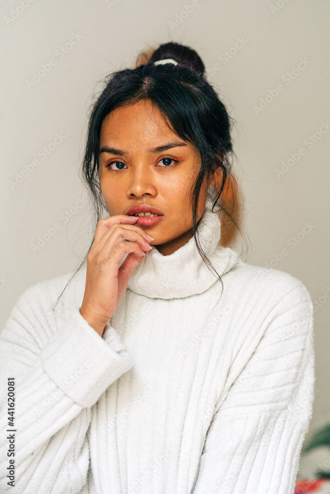 Long-haired brunette Asian woman dressed in a white sweater looking at camera Long-haired brunette Asian woman dressed in a white sweater looking at camera