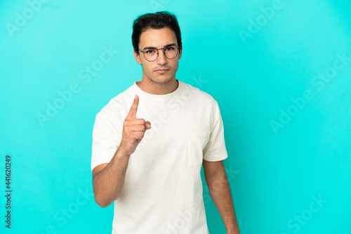Caucasian handsome man over isolated blue background frustrated and pointing to the front