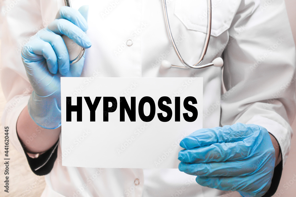 the doctor in gloves holds a card with the text HYPNOSIS . white background. the medicine the doctor in gloves holds a card with the text HYPNOSIS . white background. the medicine
