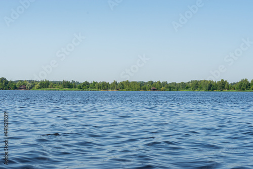 Summer landscape with blue skies and blue wavy water of a forest lake. In the middle of a warm  sunny summer with fresh green foliage. Harmony in nature