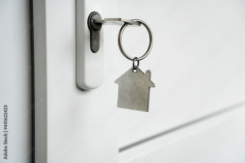 Key in the keyhole with a keychain in the form of a house Key in the keyhole with a keychain in the form of a house