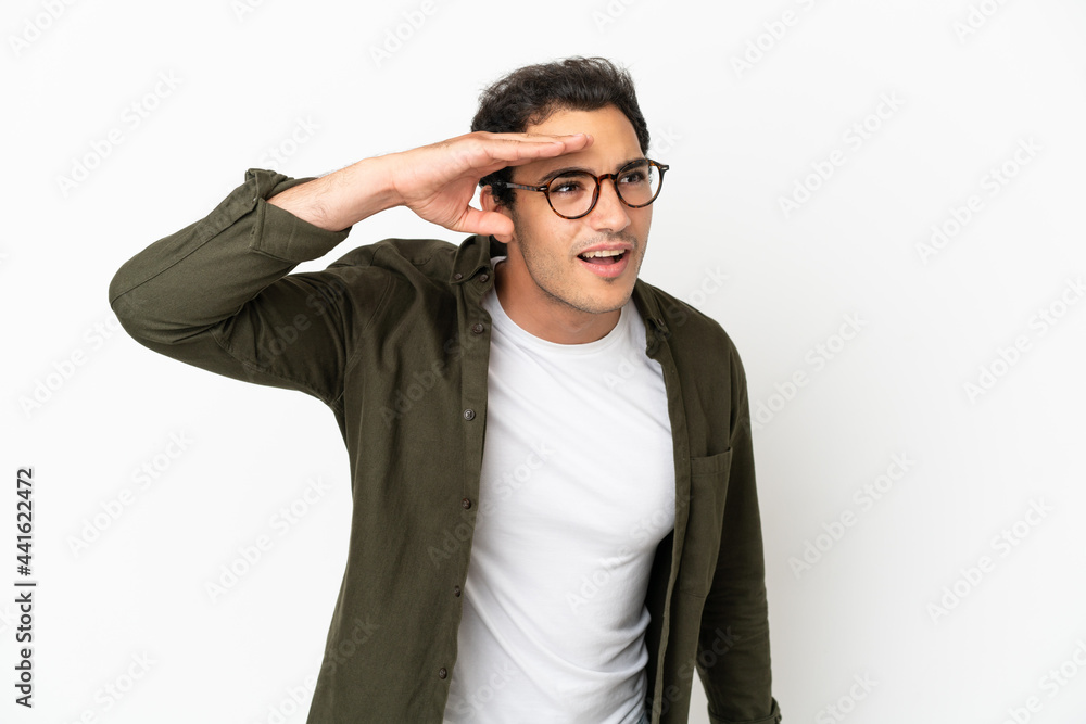 Caucasian handsome man over isolated white background looking far away with hand to look something Caucasian handsome man over isolated white background looking far away with hand to look something