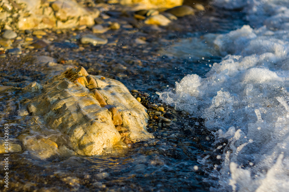pebble stones on the sea beach, the rolling waves of the sea with foam pebble stones on the sea beach, the rolling waves of the sea with foam