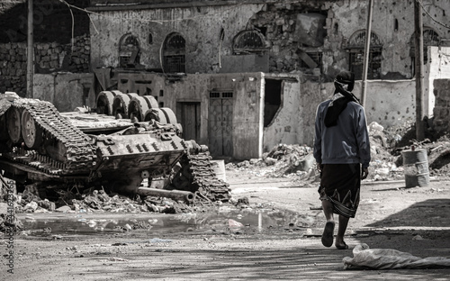 A young Yemeni man walks amid the destruction caused by the war in the city of Taiz, Yemen