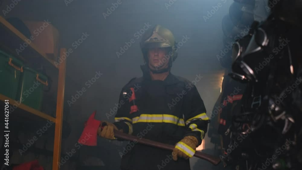 Fireman or firefighter with protective suit hold axe walk from inside room to the front then look around. Concept of staff for rescue people from fire. Fireman or firefighter with protective suit hold axe walk from inside room to the front then look around. Concept of staff for rescue people from fire.