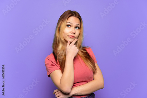 Teenager girl over isolated purple background having doubts
