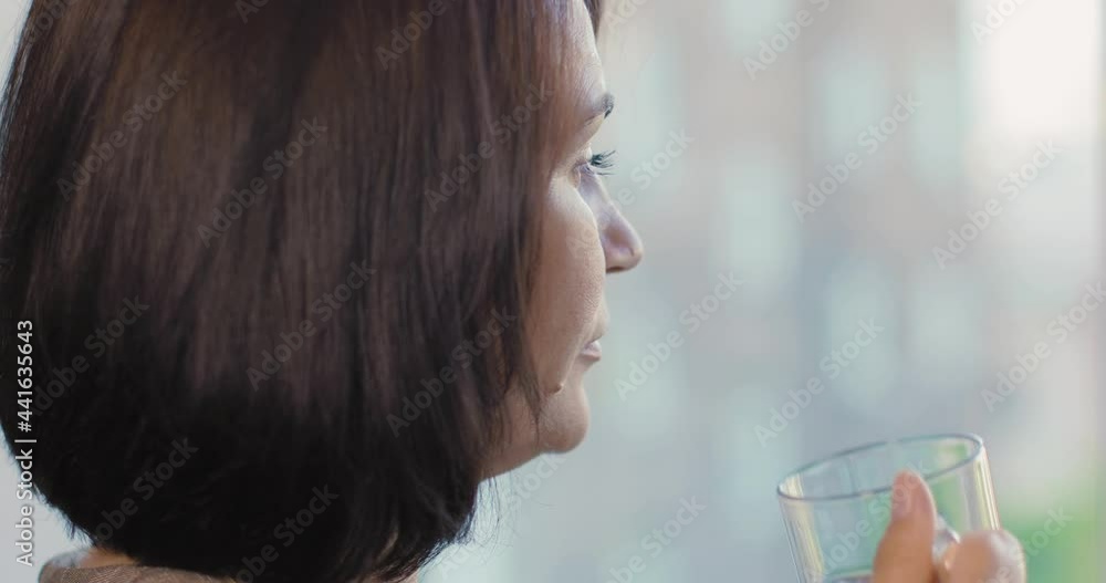 A brunette girl stands at the window and looks into the distance. She has a cup of tea in her hand. She drinks tea and thinks about her own. A brunette girl stands at the window and looks into the distance. She has a cup of tea in her hand. She drinks tea and thinks about her own.