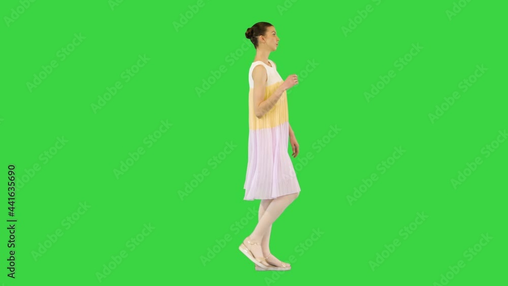 Young beautiful girl in white-yellow dress walks waving arm on a Green Screen, Chroma Key. Young beautiful girl in white-yellow dress walks waving arm on a Green Screen, Chroma Key.