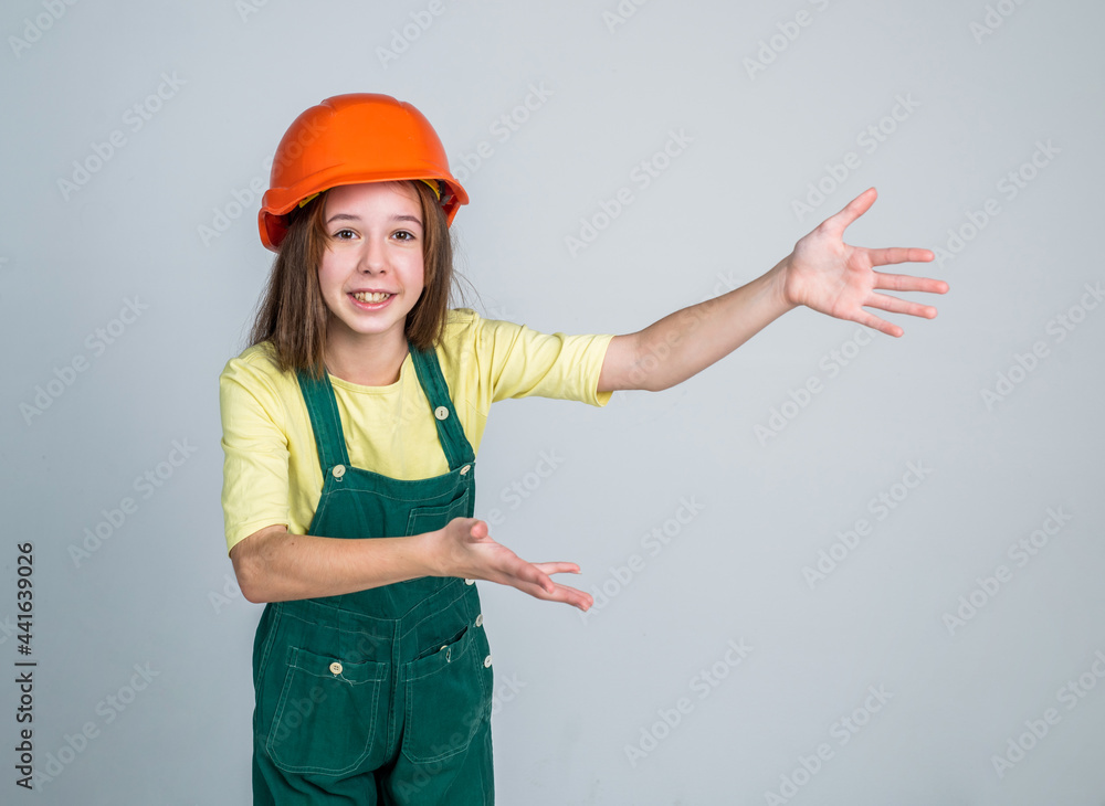 teen girl laborer in protective helmet and uniform showing copy space, gesturing teen girl laborer in protective helmet and uniform showing copy space, gesturing