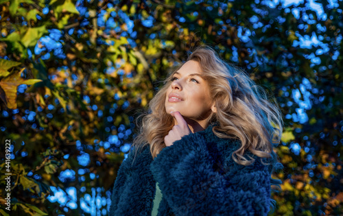 Pretty blond woman in warm faux fur coat for cold autumn weather outdoors, vogue © be free