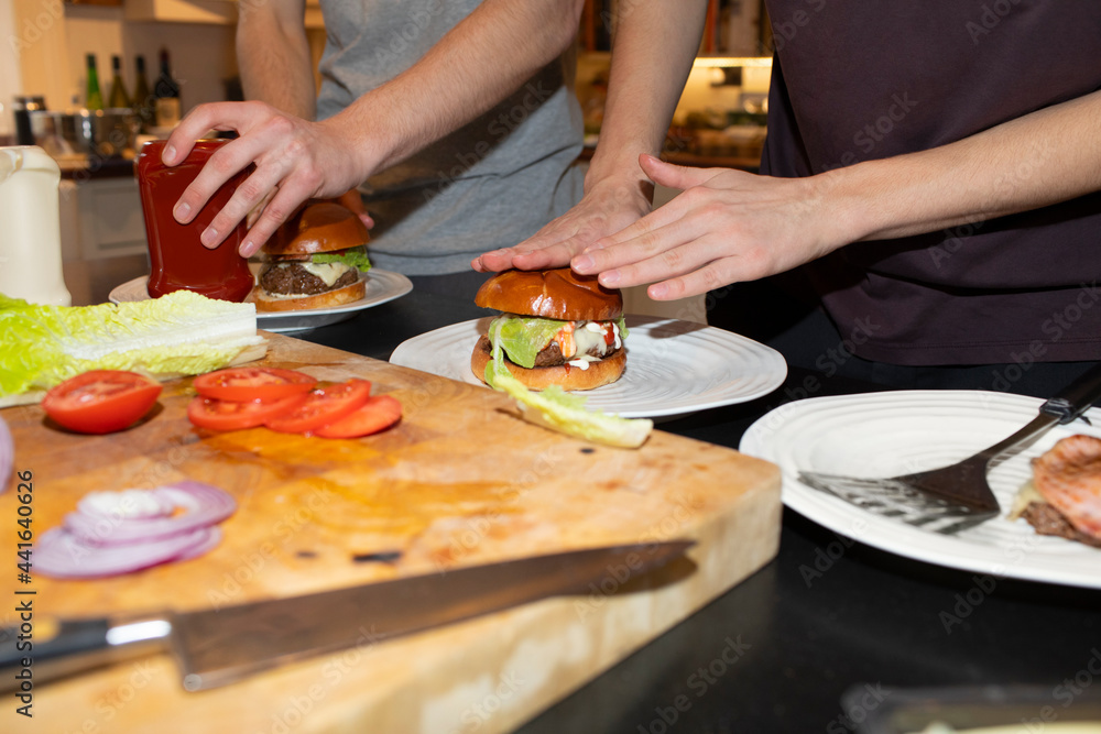 Teenage boys assembling hamburgers in kitchen Teenage boys assembling hamburgers in kitchen