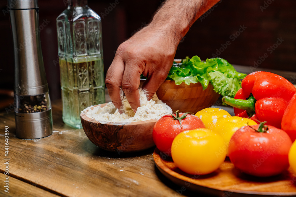 hand takes flour from a wooden bowl. ingredients for cooking. hand takes flour from a wooden bowl. ingredients for cooking.
