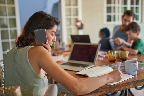Woman working from home at dining table with family