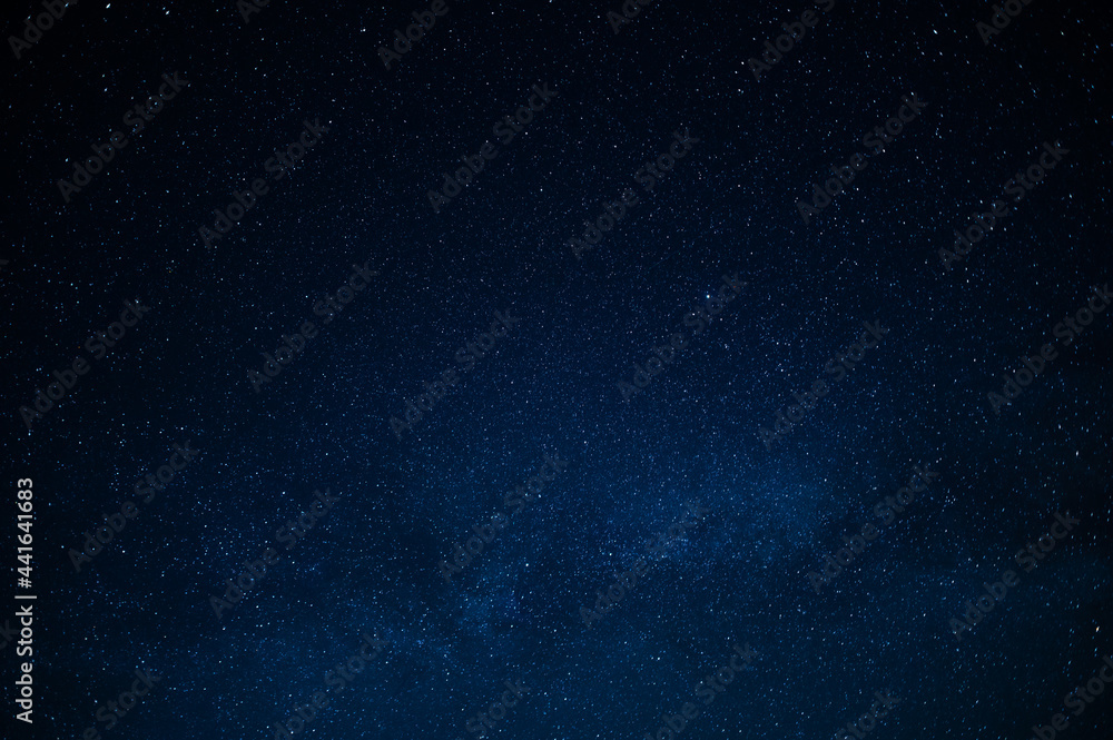 Fototapeta premium Night starry sky. Deep saturated dark blue color. Small stars twinkle far away in the sky. There is no one in the photo. There is a place for your signature. Background. Wallpaper. Texture.