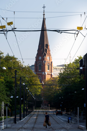 A man crossing the tramway in front of the church Allhelgonakyrkan in Lund Sweden