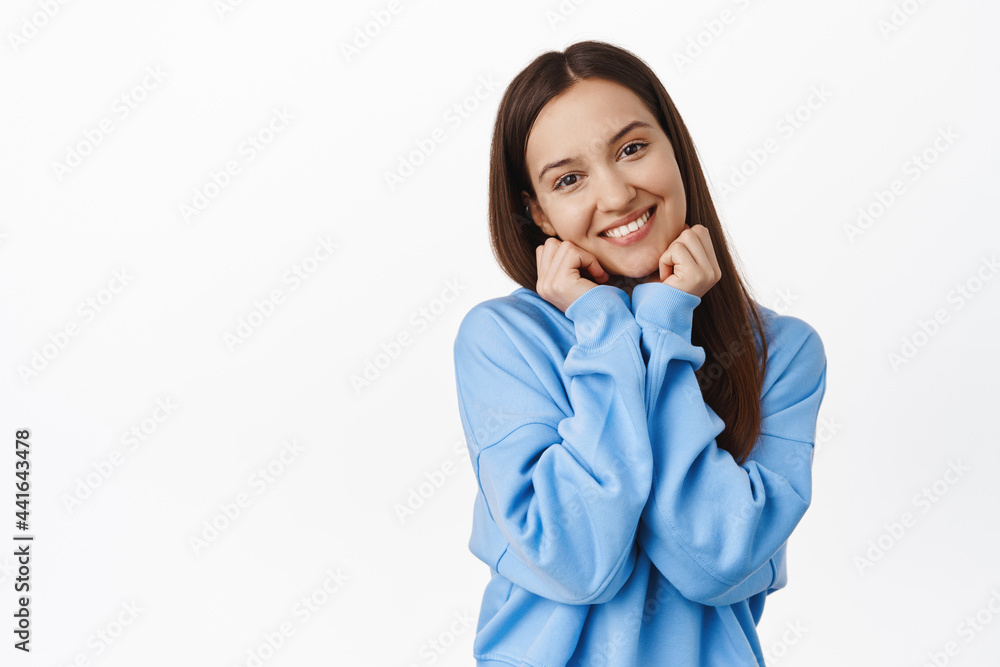 Adorable young woman with coquettish happy smile, tilt head, touching her face and blushing, flirting, gazing and contemplating smth beautiful, white background Adorable young woman with coquettish happy smile, tilt head, touching her face and blushing, flirting, gazing and contemplating smth beautiful, white background