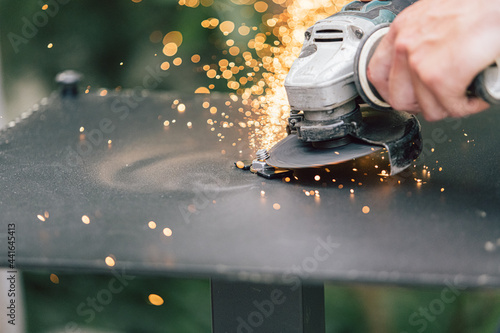 The master cuts the bolts using an angle grinder