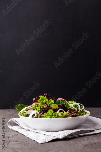 Healthy salad, leaves mix salad in a bowl over dark background. Copy space.
