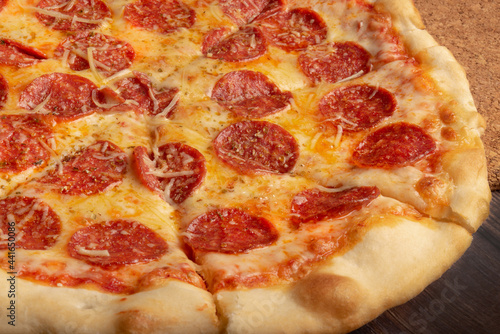 Classic Italian Pepperoni pizza on a dark wooden background. 