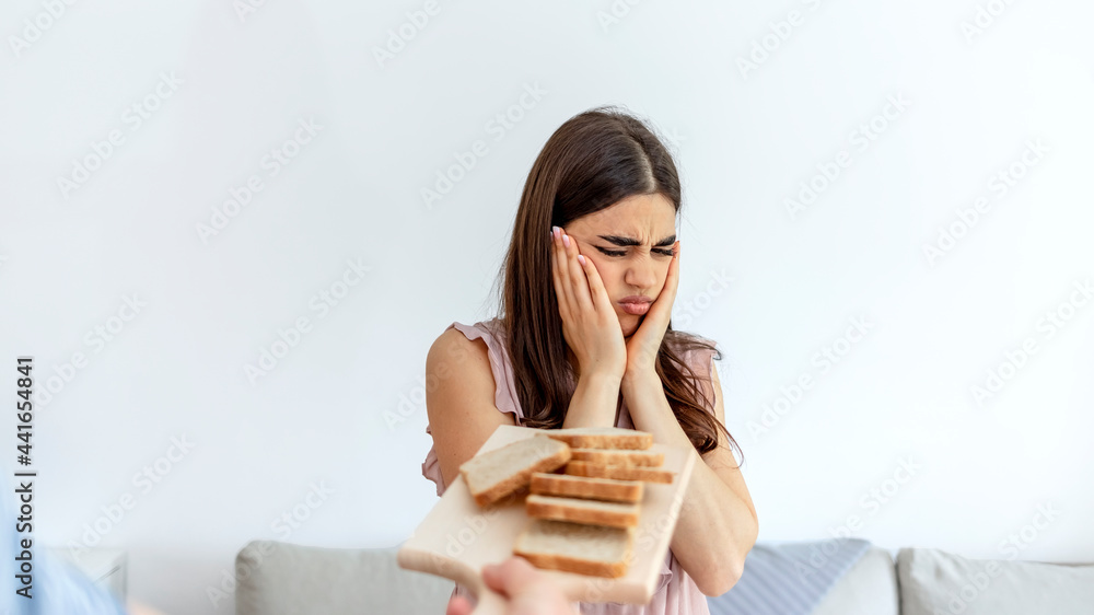 Woman refusing plate of white bread offered by a person. Gluten intolerance and diet concept. Woman refuses to eat white bread. Selective focus. Unhappy woman rejecting to eat bread. Copy space. Woman refusing plate of white bread offered by a person. Gluten intolerance and diet concept. Woman refuses to eat white bread. Selective focus. Unhappy woman rejecting to eat bread. Copy space.