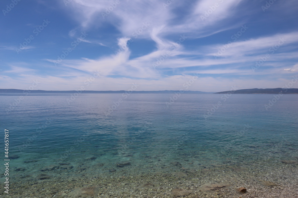 Picturesque seascape white clouds in blue sky over turquoise sea on summer sunny day, Croatia.  Beach with transparent aquamarine water of the sea and clouds in the form of a heart pattern in the sky