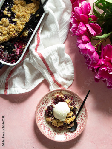 Berry crumble with lilac peonies on a pink background. Top view. close up.