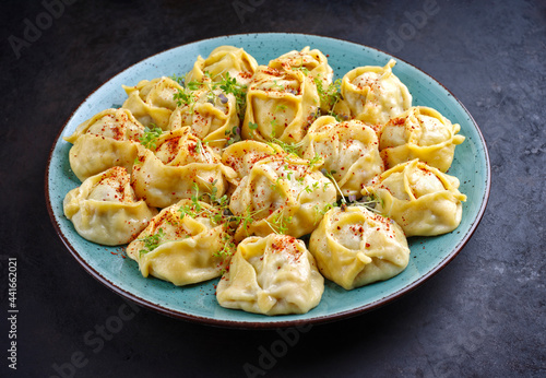 Traditional steamed Kazakh manti garnished with mincemeat and sumah served as close-up on a Nordic design plate with copy space photo