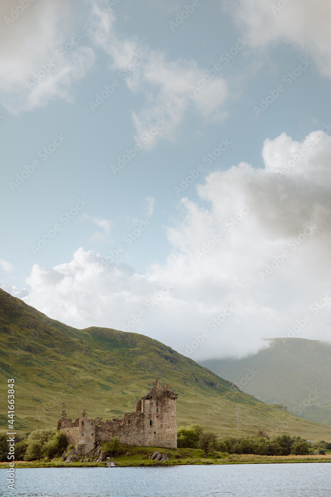 Ancient castle against hills on lake coast Ancient castle against hills on lake coast