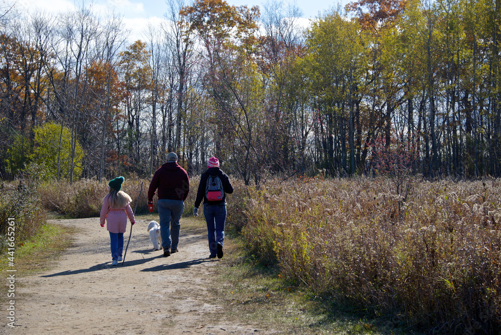 Toronto, Ontario / Canada - October 31, 2020: Family hiking in the forest footpath with social distancing. Toronto, Ontario / Canada - October 31, 2020: Family hiking in the forest footpath with social distancing.