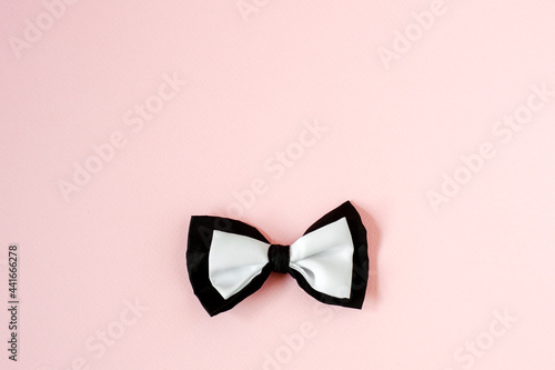 Black and white bow tie on a pastel pink Copy space background.