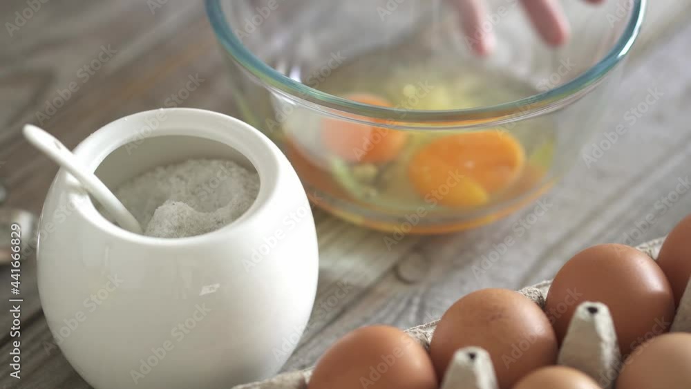 Hands of young housekeeper add salt while preparing dough in bowl. Woman's hand takes pinch of salt from jar. Making Belgian waffle dough or dough at home. Tray of eggs in the foreground. Step 3 recip Hands of young housekeeper add salt while preparing dough in bowl. Woman's hand takes pinch of salt from jar. Making Belgian waffle dough or dough at home. Tray of eggs in the foreground. Step 3 recip