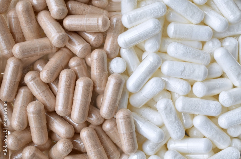 Vitamins and supplements. Lots of white and beige capsules as a background. Vitamins and supplements. Lots of white and beige capsules as a background.