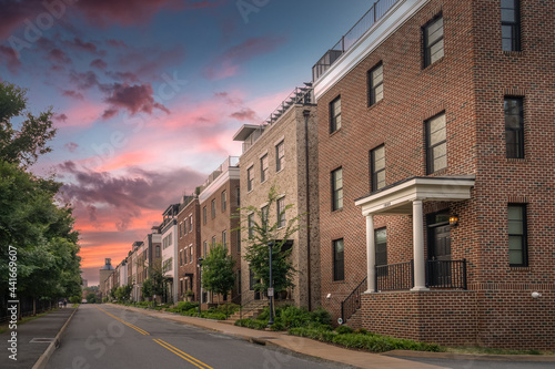 Newly built multi story luxury single family homes lining up next to an old railway station and coal tower on Water street in Charlottesville Virginia with dramatic colorful sunset sky