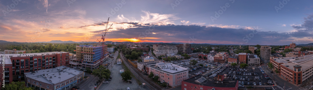 Aerial sunset view of downtown Charlottesville, Virginia with new construction office apartment building, city market parking lot, parking garage and the mall with dramatic colorful purple orange sky 