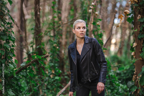 Tough Young Woman in a Black Leather Jacket Exploring a Forest Area