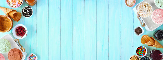 Summer ice cream buffet with a mixture of flavors and sweet toppings. Top view table scene on a blue wood background.