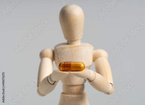 Wooden mannequin with pills on white background.