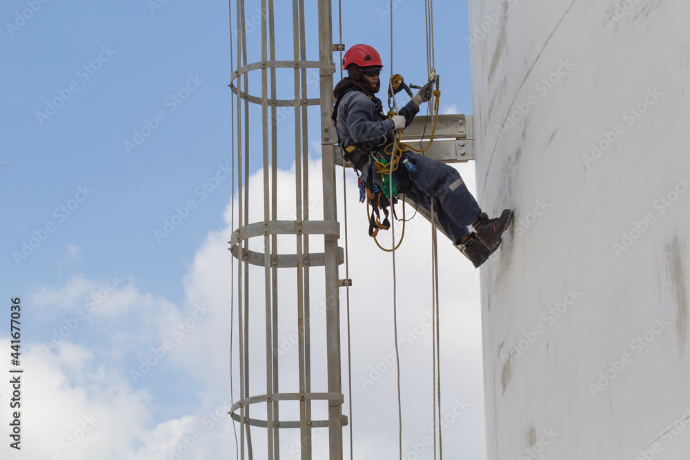 Fototapeta premium Male worker rope access inspection of thickness storage tank industry