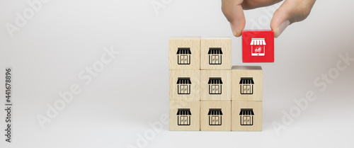 Franchise, Hand choosing cube wooden blocks stack with franchise business store E-commerce smartphone with graph icon for business growth and change to online financial marketing concepts. photo