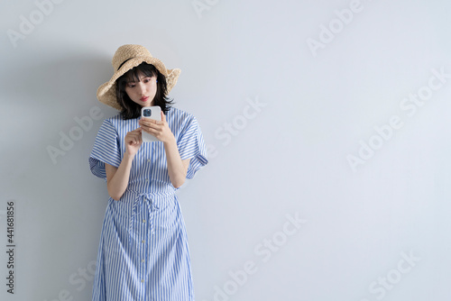 スマートフォンを使う麦わら帽子の女性
