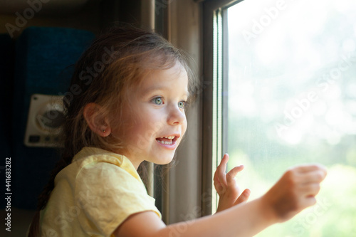 A little girl looks out the train window with interest. Travelling with a child. vacation. curiosity. summer.