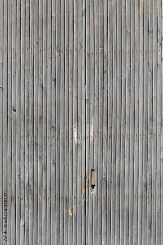 Natural background from a simple fence made of old rough wooden planks with the texture of unsmiled wood.