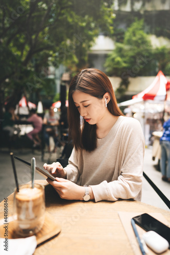 Young adult business asian woman use tablet for business at outdoor city lifestyle cafe.