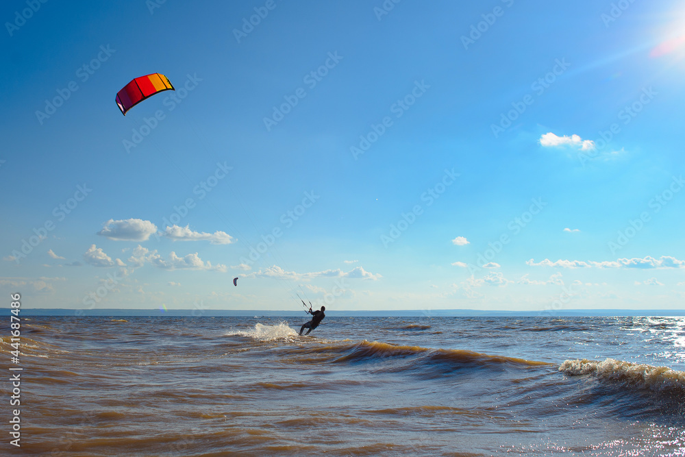 Kiteboarder surfing waves with kiteboard on a sunny summer day.