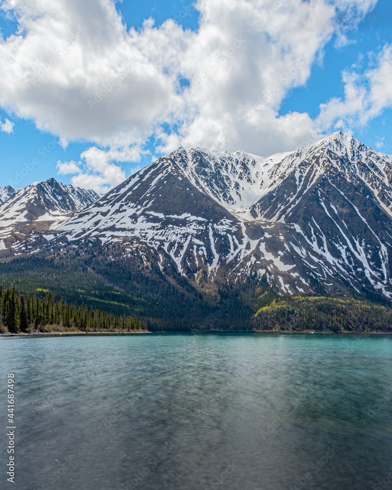 Stunning landscape beautiful view of Kathleen Lake in Yukon Territory, northern Canada with calm, pristine lake below snow capped mountain peaks in May, spring time. 