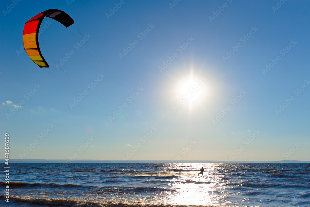 Kiteboarder surfing waves with kiteboard on a sunny summer day. Kiteboarder surfing waves with kiteboard on a sunny summer day.
