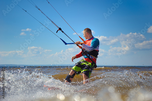 Kiteboarder surfing waves with kiteboard on a sunny summer day. © sheikoevgeniya